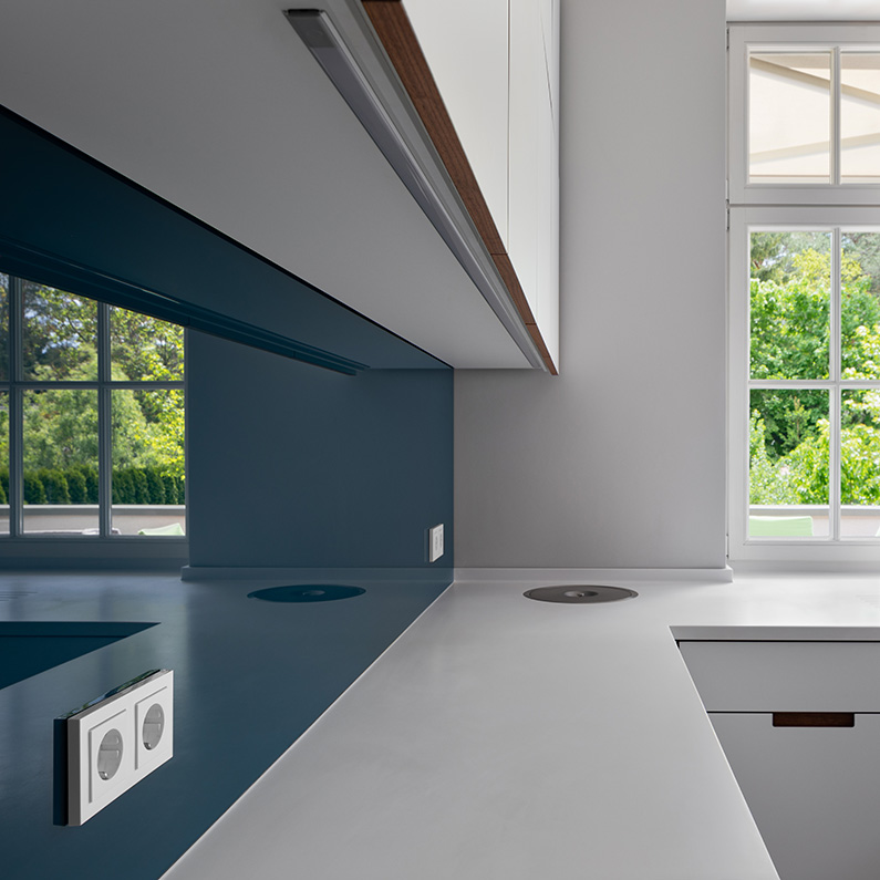 Arbeitsfläche in einer Küche. In der dunkelblauen Rückwand spiegelt sich ein Fenster.