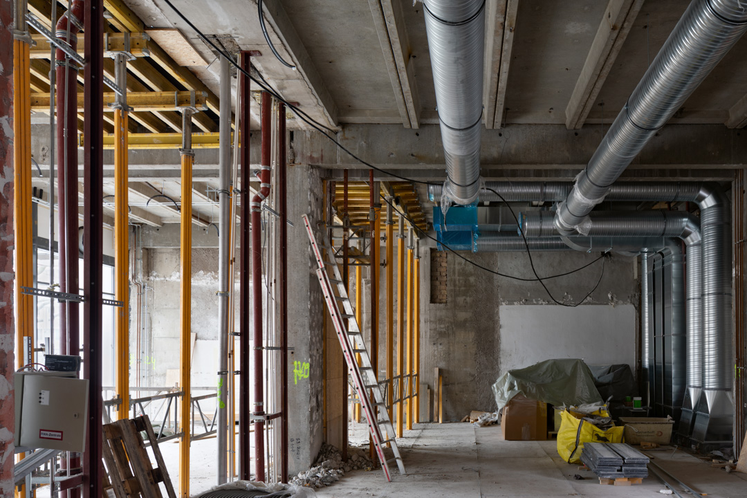 Architekturfoto von einer Baustelle im Innenraum mit offen liegenden Heizungsrohren.