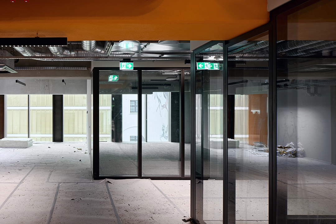 Architekturfotografie einer Baustelle, die fast fertig gestellt ist. Eine offene Fabriketage mit Büroeinheiten als Glaskonstruktionen.