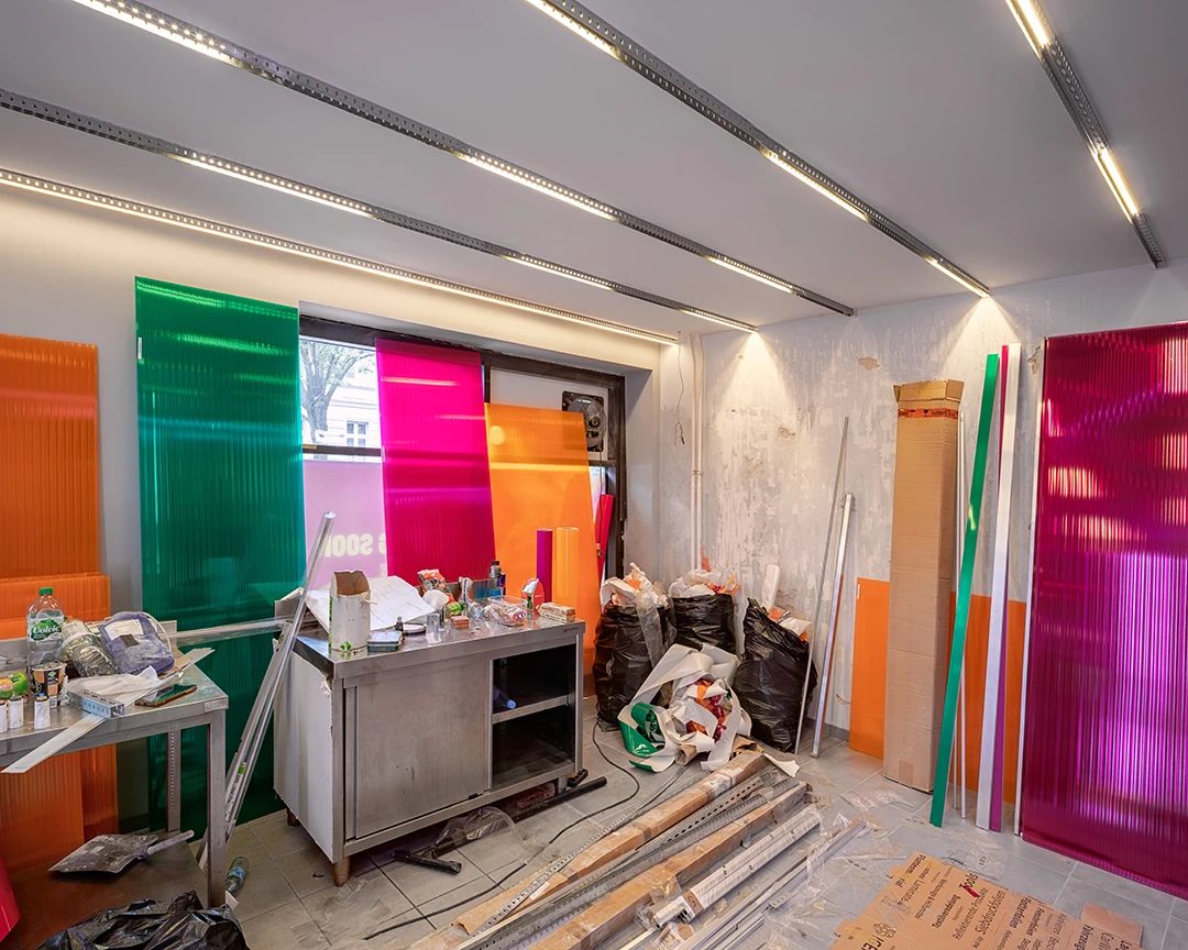 Architekturfoto von einer Baustelle. Geradlinige Lichtführung, bunte Panele stehen an der Wand.