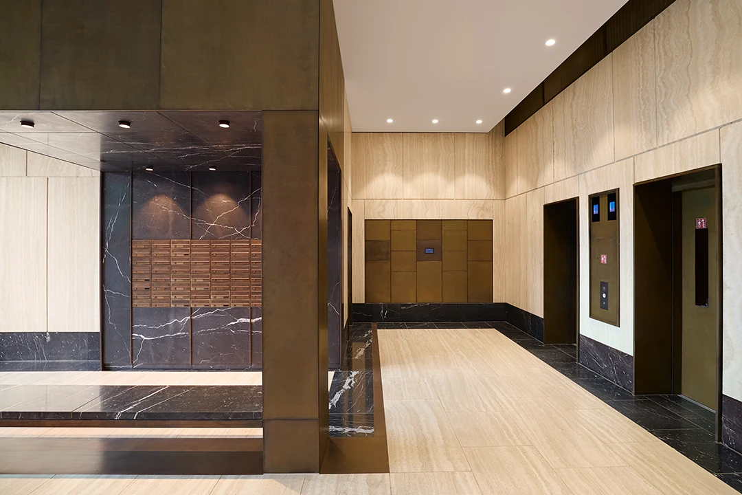Architekturfotografie eines Foyers mit Bronzeeinbauten, Steinböden und Steinwänden, warme Athmosphäre