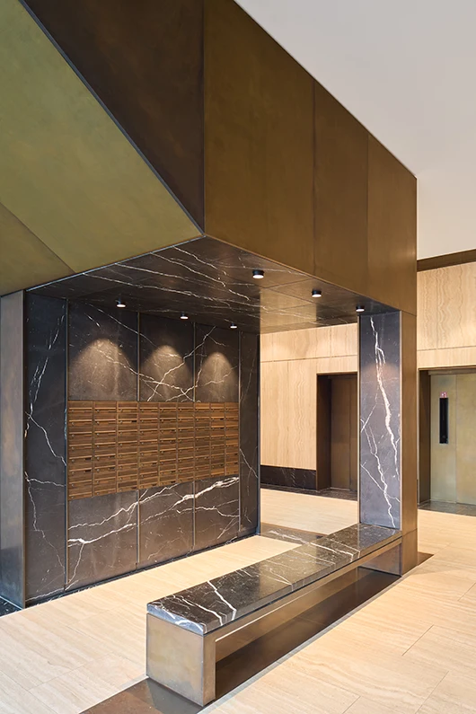 Architekturfotografie von einem Foyer in braunem und schwarzem Stein mit Einbauten aus Bronze, warme Athmosphäre.