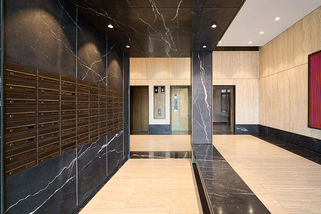 Architekturfotografie von einem Foyer, in schwarzem und braunem Naturgestein gehalten mit Einbauten aus Bronze, warme Athmosphäre