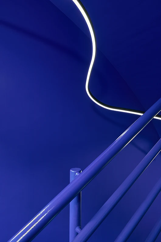 Detailaufnahme im kräftig blauen Treppenhaus des Exilmuseums Berlin. Blaue Wände, blaue Geländer.